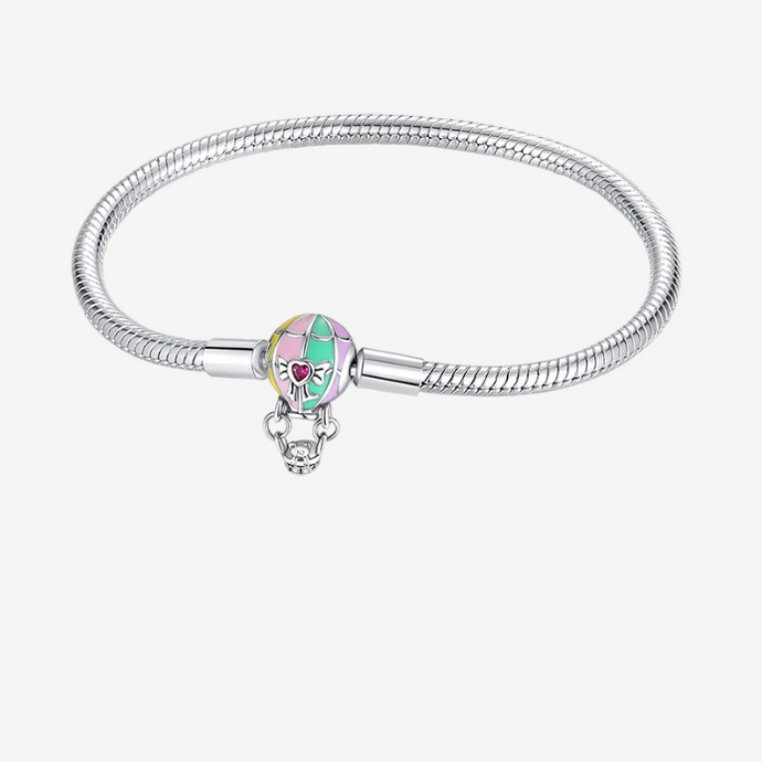 Silver bracelet with a heart-shaped charm on a pink background